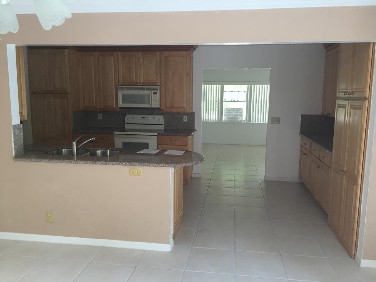 9276 Saddlebrook Drive Boca Raton, FL 33496 - Photo 2 of 10 a kitchen with granite countertop a refrigerator and a stove
