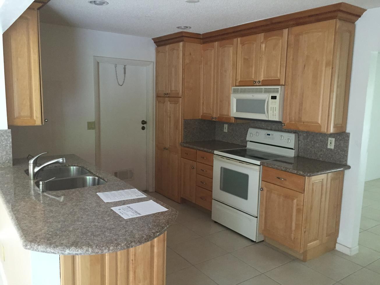 9276 Saddlebrook Drive Boca Raton, FL 33496 - Photo 3 of 10 a kitchen with stainless steel appliances granite countertop a sink stove and microwave