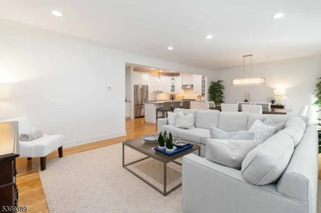 a kitchen with stainless steel appliances granite countertop a refrigerator a stove a sink a dining table and chairs with wooden floor