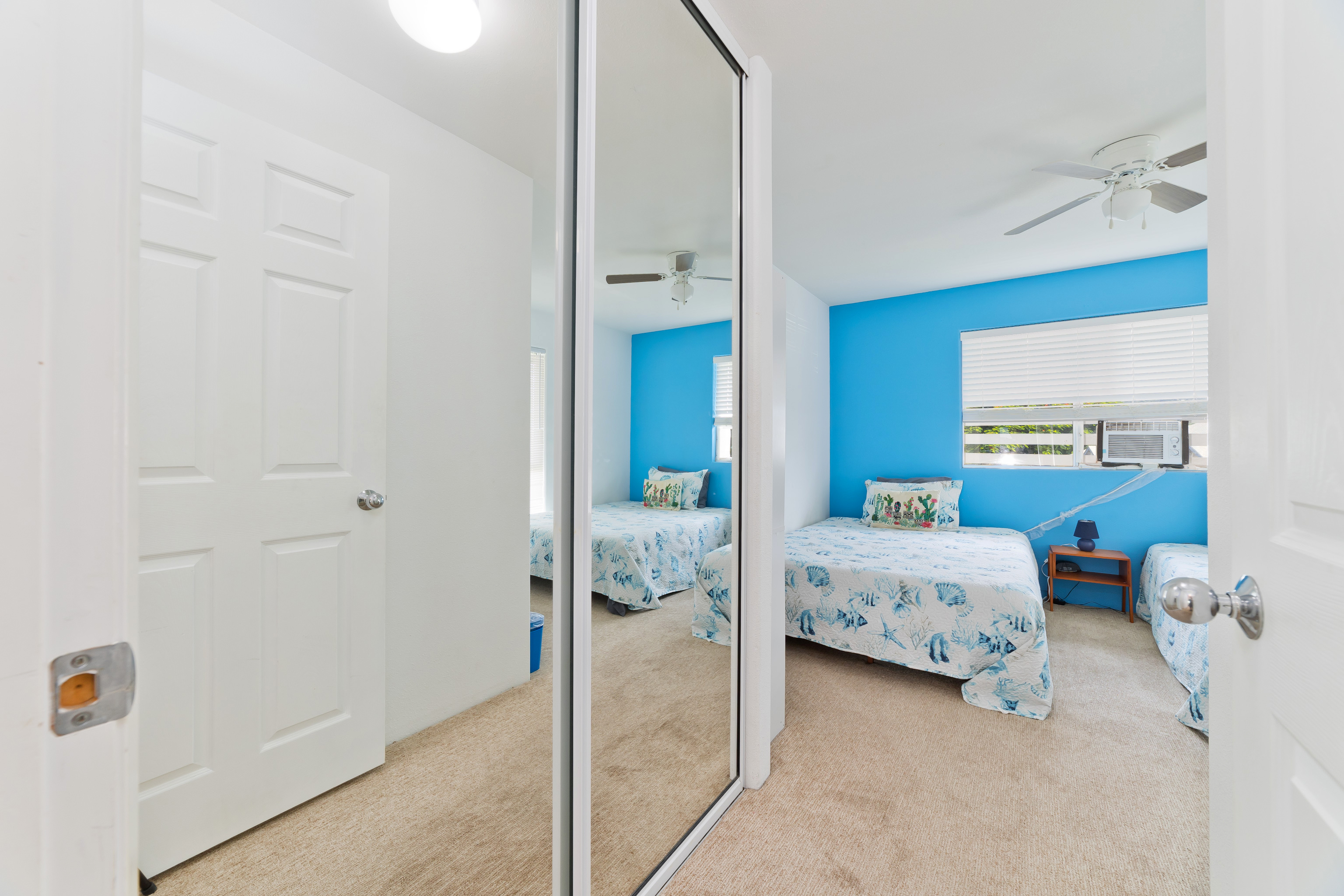 75-6081 Alii Drive, Unit O201 Kailua-Kona, HI 96740 - Photo 18 of 28 a bedroom with a bed and a chandelier