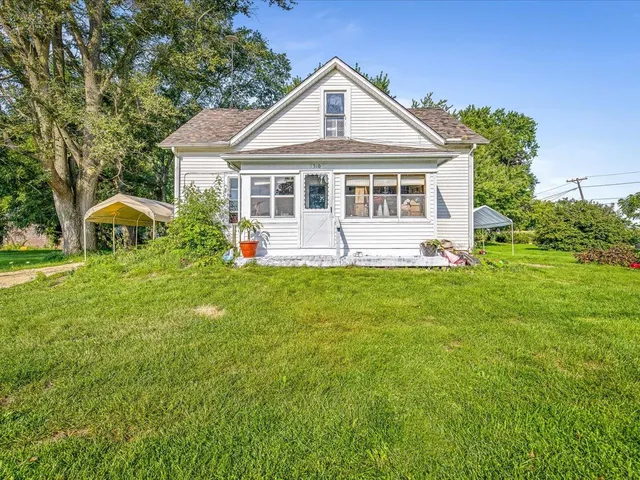 a front view of house with garden and trees
