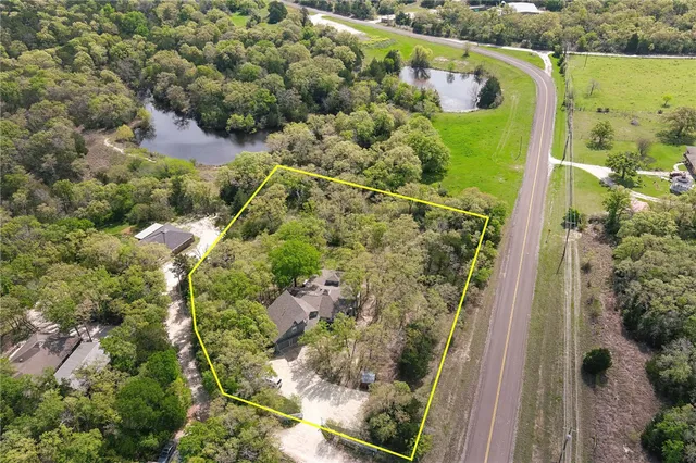 an aerial view of residential houses with outdoor space and trees