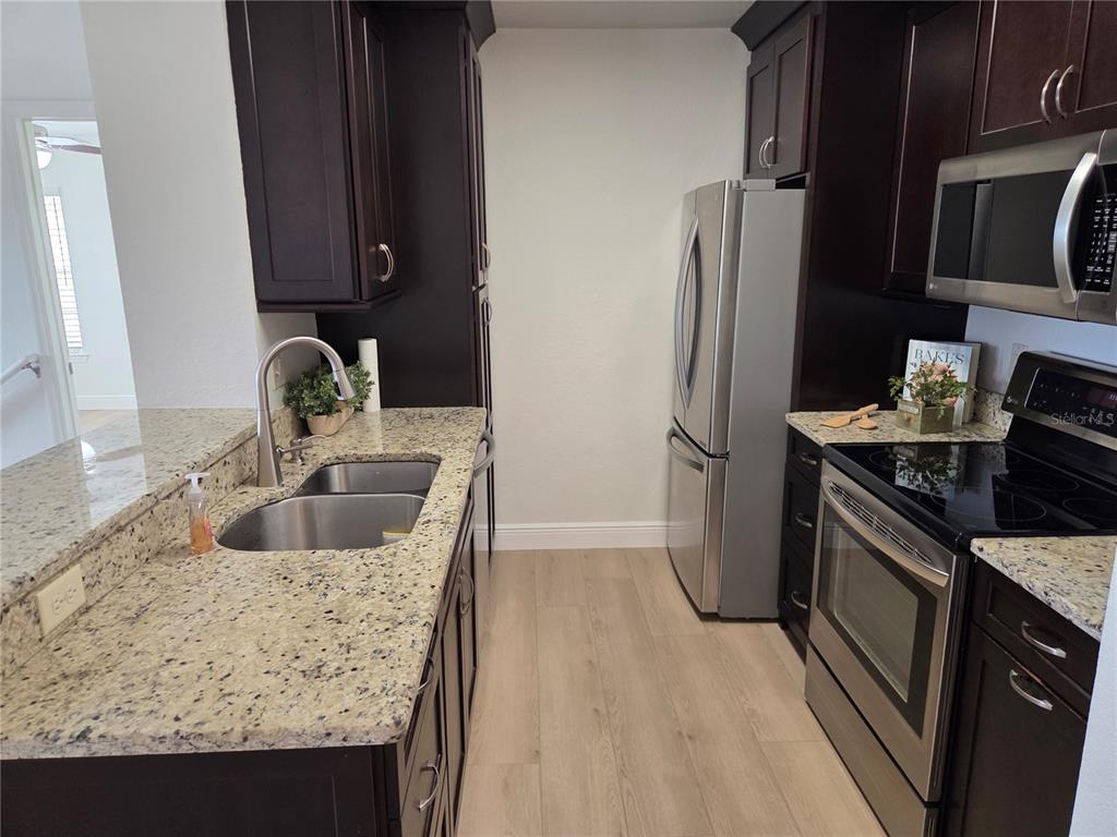 8905 Manor Loop, Unit 205 Lakewood Ranch, FL 34202 - Photo 10 of 30 a kitchen with stainless steel appliances granite countertop a sink stove and refrigerator