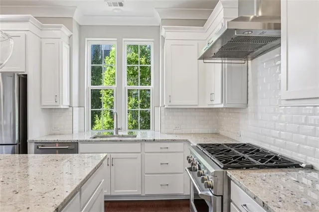 a kitchen with granite countertop a sink stainless steel appliances and window