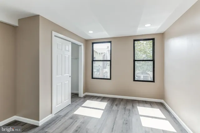 an empty room with wooden floor and windows