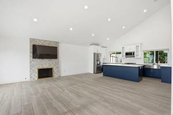 a large kitchen with stainless steel appliances kitchen island a large counter top a oven and a fireplace