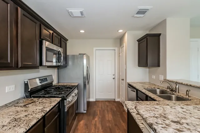a kitchen with stainless steel appliances granite countertop a stove top oven a sink dishwasher and a refrigerator