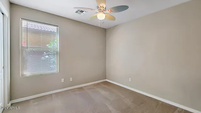 an empty room with a window and a fan