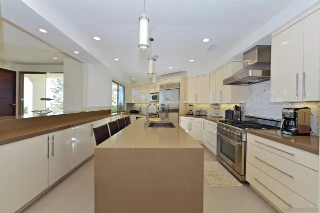 a large white kitchen with lots of counter space sink and appliances