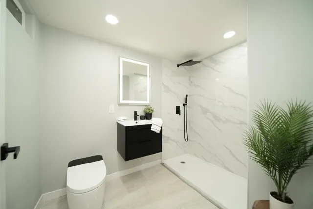 a bathroom with a granite countertop sink a toilet and shower