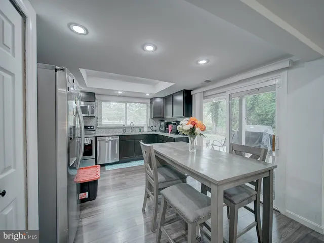 a dining room with stainless steel appliances granite countertop a table chairs and a wooden floor