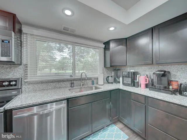 a kitchen with stainless steel appliances kitchen island granite countertop a refrigerator and a sink