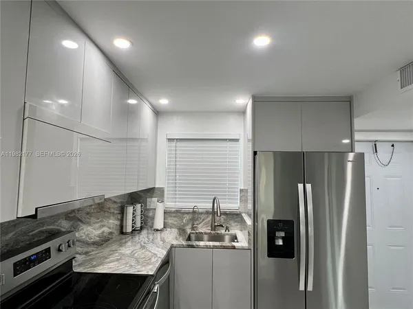 a kitchen with stainless steel appliances granite countertop a refrigerator a sink and a stove