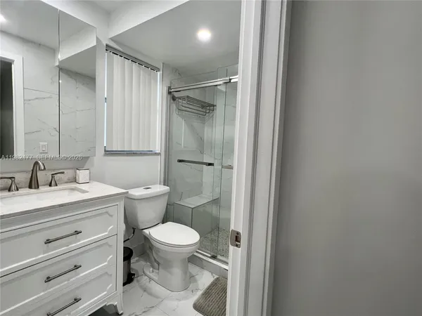 a bathroom with a granite countertop toilet a sink and a mirror