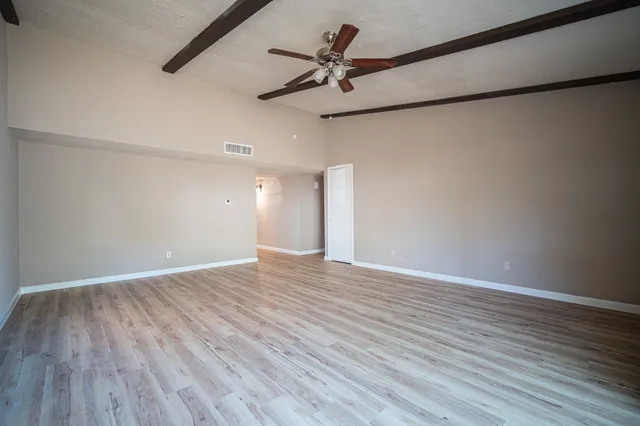 a view of an empty room with a window and wooden floor
