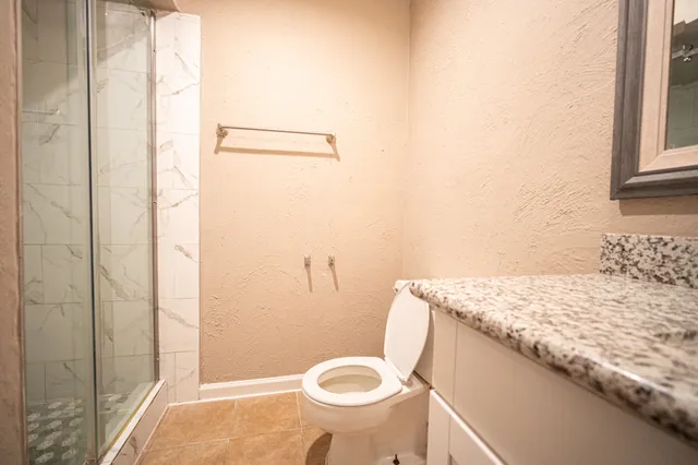 a bathroom with a granite countertop toilet and a sink