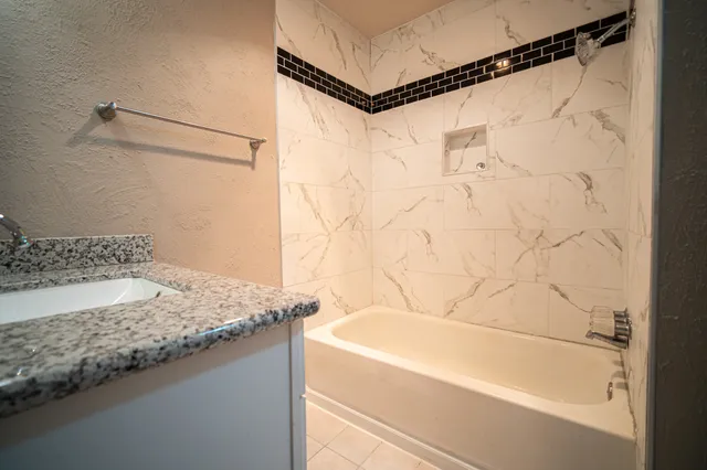 a bathroom with a granite countertop sink and a bathtub