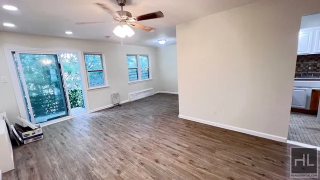 a view of an empty room with a window and wooden floor