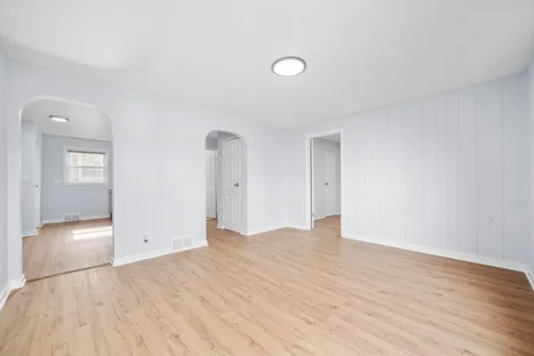 a view of an empty room with wooden floor and a bathroom
