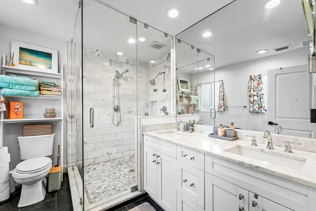 a bathroom with a granite countertop sink toilet a large mirror a shower and vanity