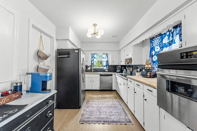 a kitchen with granite countertop a refrigerator stove top oven and sink