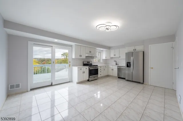a large white room with a large window and kitchen view