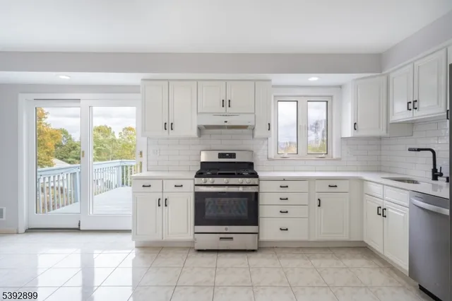 a kitchen with white cabinets appliances and a window