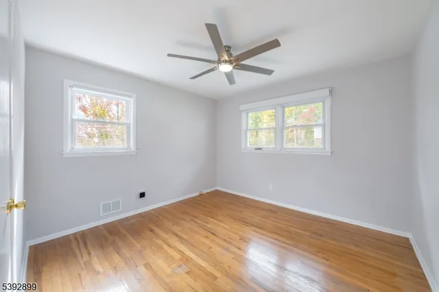 a view of empty room with wooden floor and fan