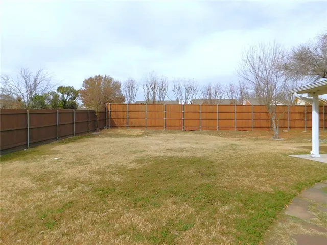 a view of a yard with wooden fence