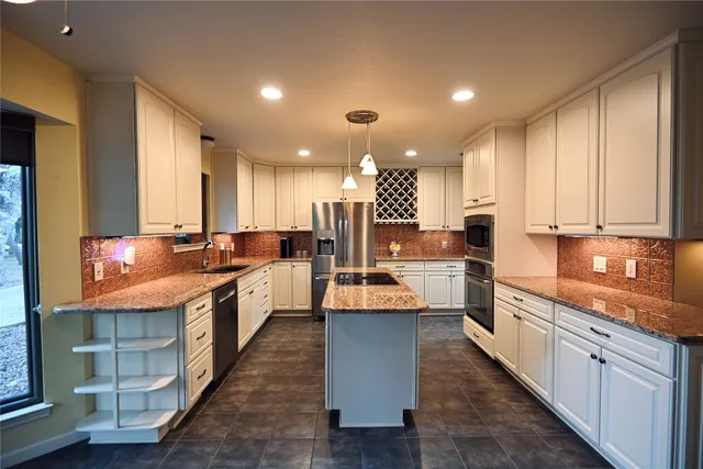 a large kitchen with stainless steel appliances lots of counter space and a sink
