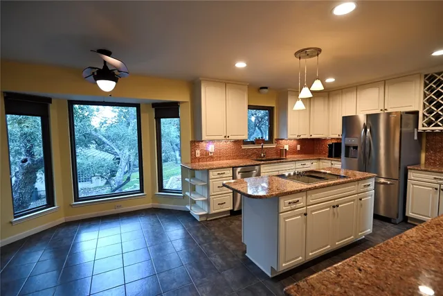 a kitchen with kitchen island granite countertop a stove and a refrigerator
