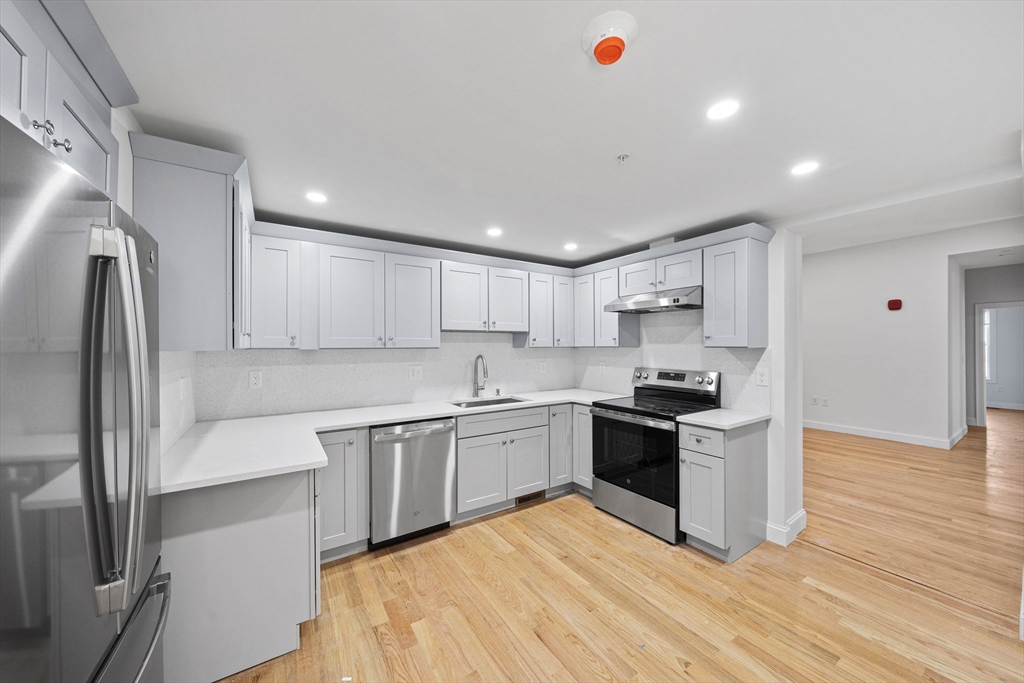 a large kitchen with stainless steel appliances granite countertop a stove and a refrigerator