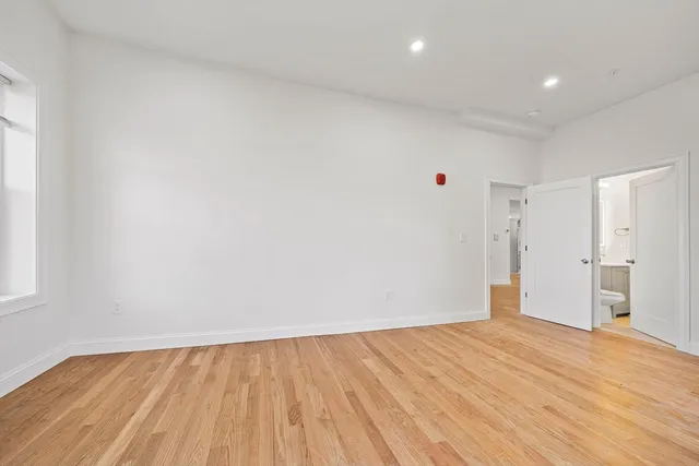 a view of an empty room with wooden floor and cabinets