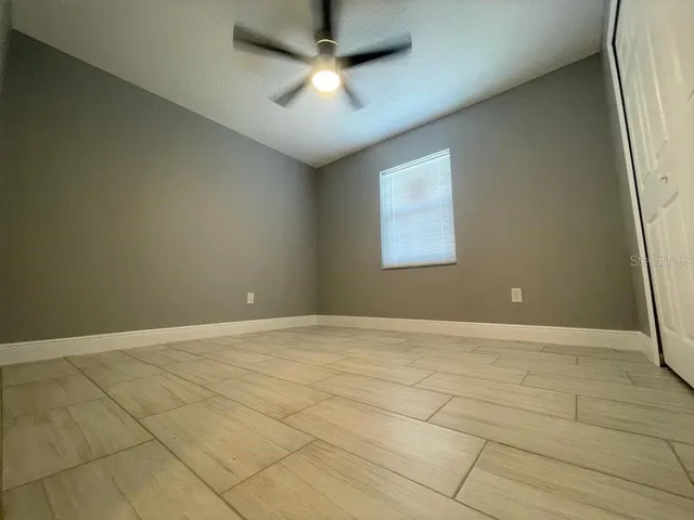 an empty room with a ceiling fan and window