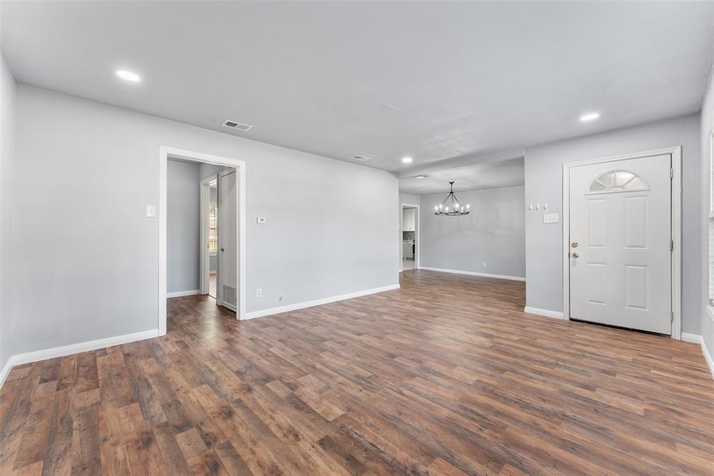 612 East 8th Street Kemp, TX 75143 - Photo 4 of 25 Spacious interior featuring wood-finish flooring, light gray wall paint, recessed lighting, and a white paneled entry door with an arched window insert