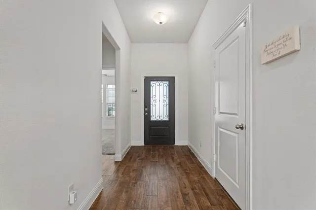 a view of a hallway with wooden floor and a bathroom