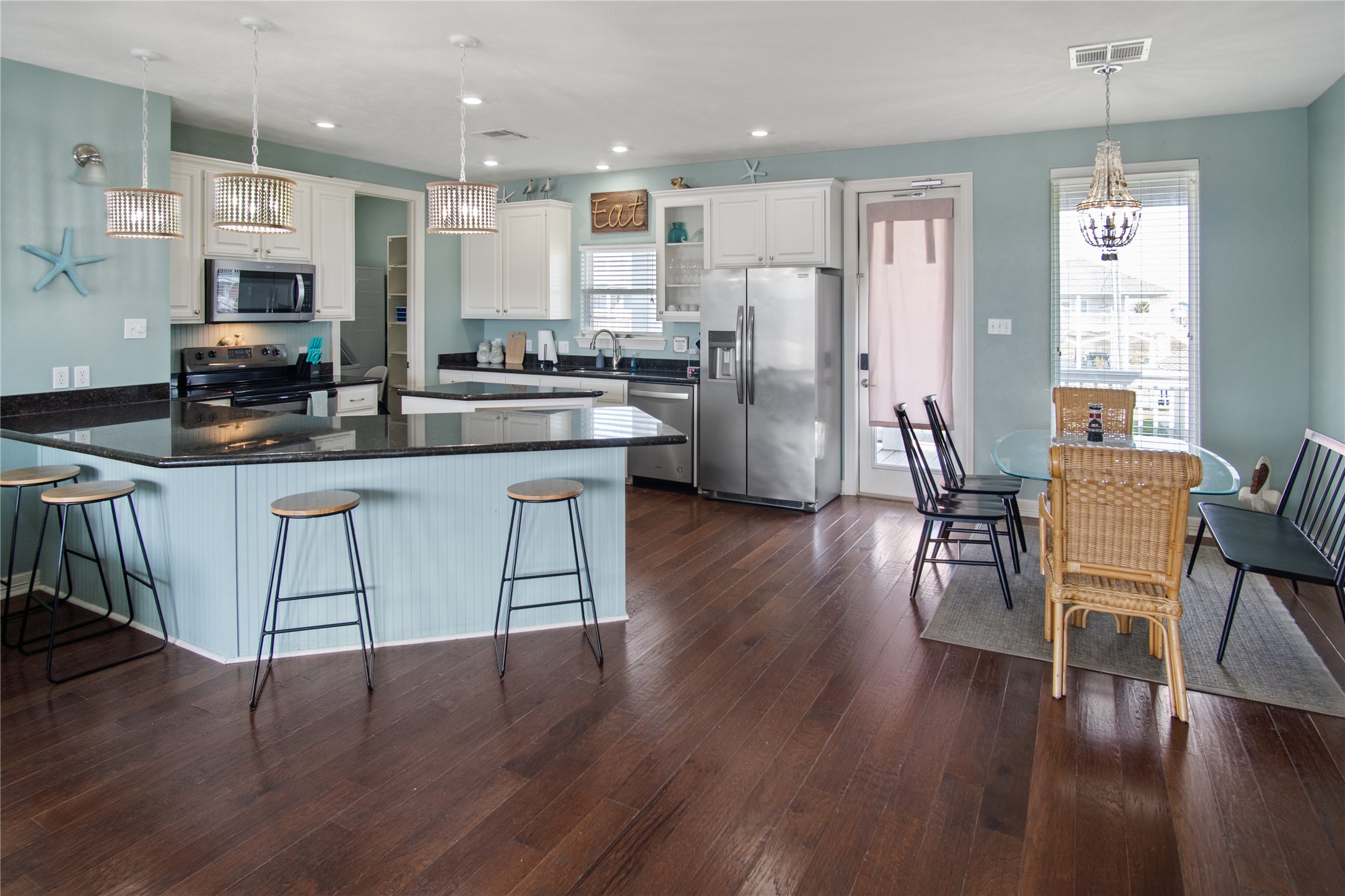 932 Kent Crystal Beach, TX 77650 - Photo 7 of 37 a kitchen with stainless steel appliances granite countertop a refrigerator a stove top oven a sink dishwasher and white cabinets with wooden floor