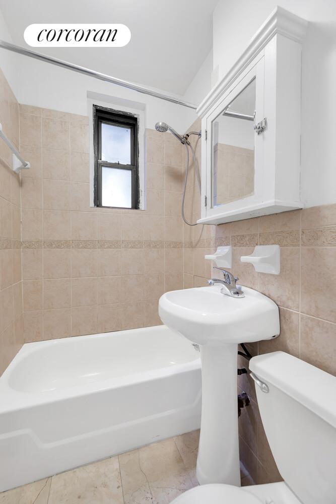 21-28 35th Street, Unit 1H Queens, NY 11105 - Photo 7 of 8 a bathroom with a sink a toilet and a mirror