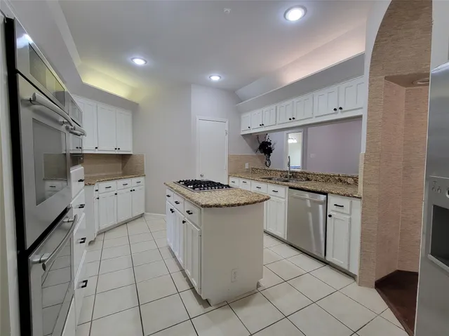 a kitchen with granite countertop a sink stove and cabinets