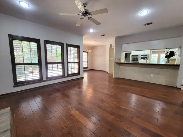 an empty room with wooden floor chandelier and windows
