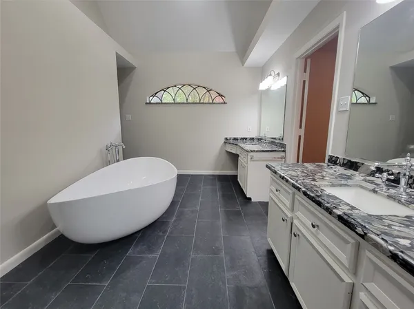 a spacious bathroom with a granite countertop sink a toilet mirror and a bathtub
