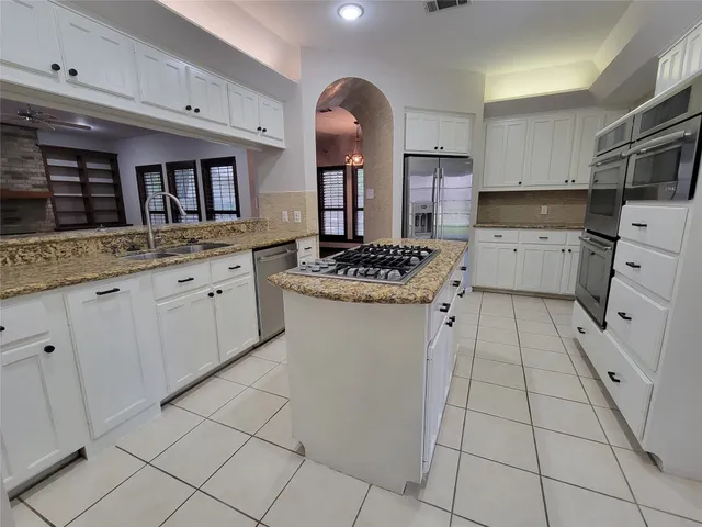 a kitchen with stainless steel appliances granite countertop a stove a sink and a refrigerator