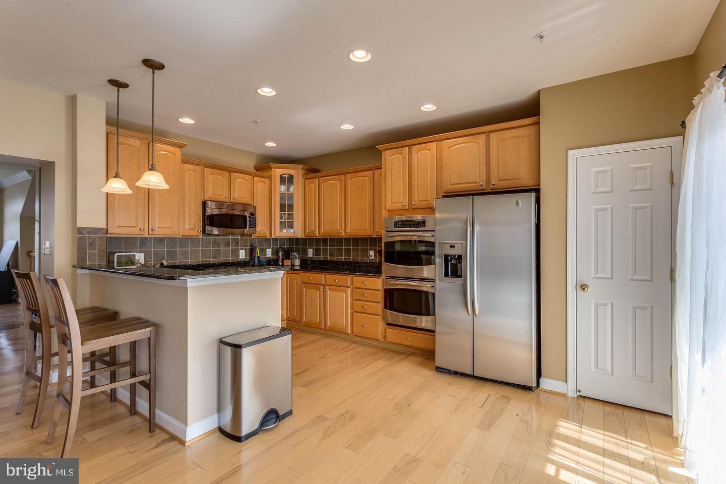 14233 B St Germain Drive, Unit 6 Centreville, VA 20121 - Photo 5 of 13 a kitchen with kitchen island granite countertop white cabinets and stainless steel appliances