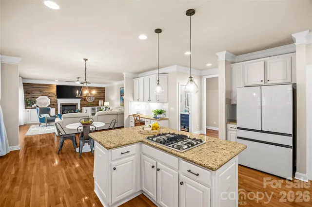 a kitchen with a stove a refrigerator a oven a dining table and chairs with wooden floor