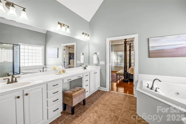 a bathroom with a tub a double vanity sink a mirror a window and vanity