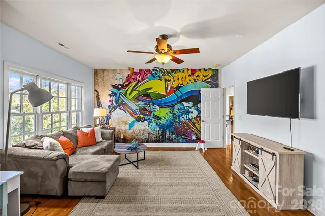 a living room with furniture a flat screen tv and a floor to ceiling window