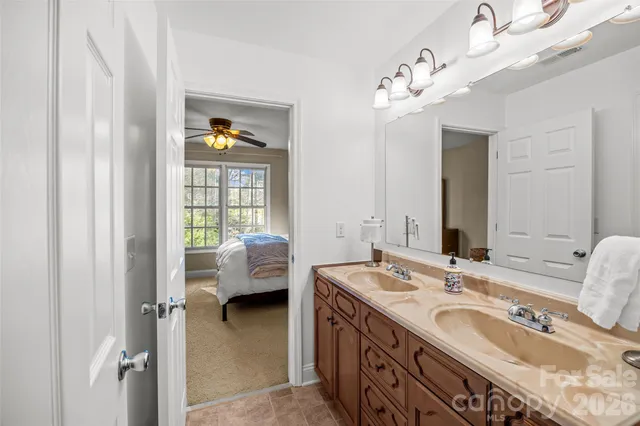 a en suite bathroom with a granite countertop double vanity and a mirror