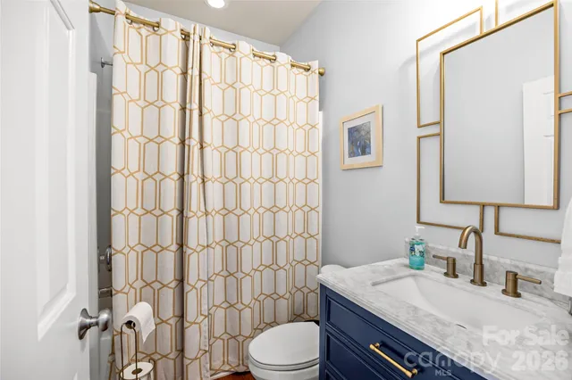 a bathroom with a granite countertop sink toilet a mirror and shower curtain