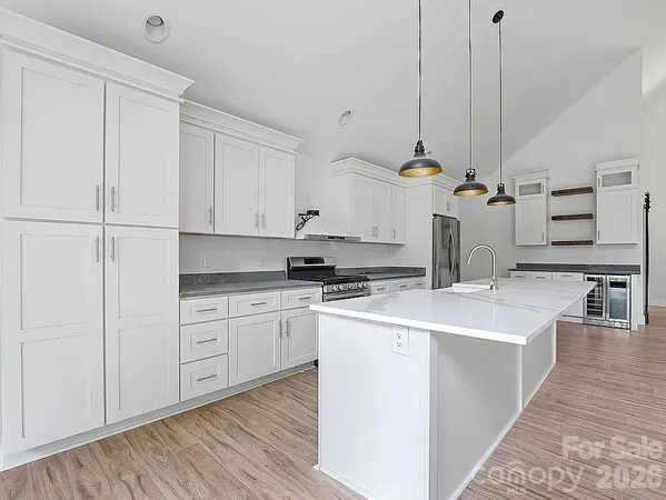 a kitchen with kitchen island a sink a stove a refrigerator and white cabinets