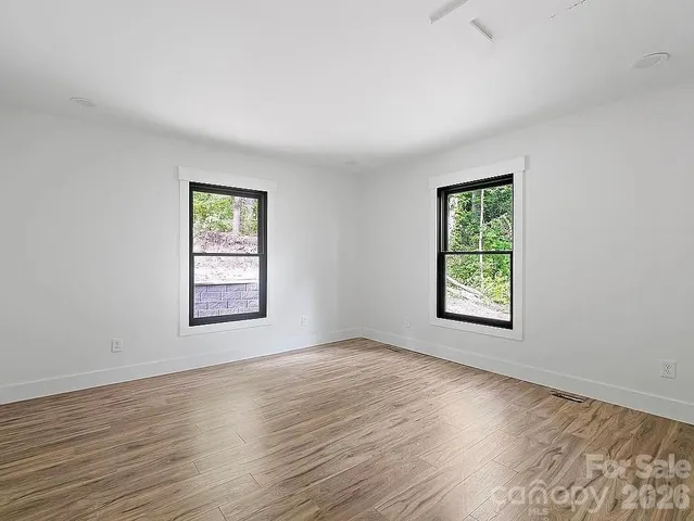 an empty room with wooden floor and windows